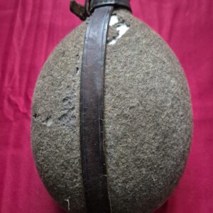 A worn German WWII felt-covered canteen with leather strap and metal cap.